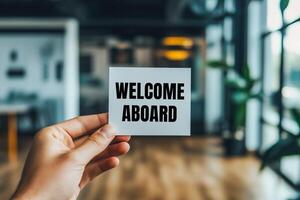 Welcome aboard message written on white paper with blurry office background. Conceptual welcome aboard symbol. Copy space. photo