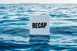 Recap word written on a white card on sea. Conceptual recap word symbol. photo