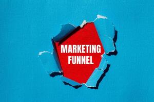 Marketing funnel message written on ripped torn blue paper with red background. Conceptual marketing funnel symbol. Copy space. photo