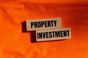 Property investment message written on wooden blocks with orange background. Conceptual property investment symbol. Copy space. photo