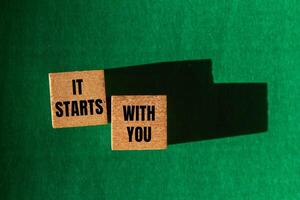It starts with you message written on wooden cubes on green background. Conceptual it starts with you symbol. Copy space. photo