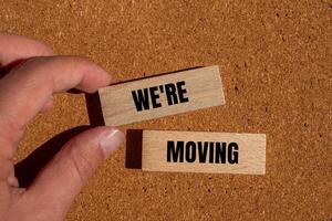 We are moving message written on wooden blocks with brown background. Conceptual we are moving symbol. Copy space. photo