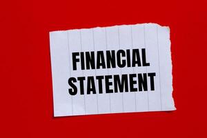 Financial statement message written on ripped torn paper piece with red background. Conceptual financial statement symbol. Copy space. photo