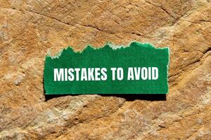 Mistakes to avoid message written on ripped torn green paper piece on stone background. Conceptual mistakes to avoid symbol. Copy space. photo
