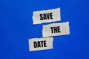 Save the date words written on ripped torn paper pieces with blue background. Conceptual save the date symbol. Copy space. photo