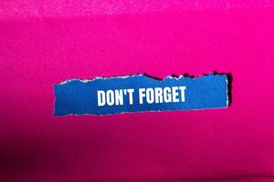 Don't forget message written on ripped torn blue paper piece with pink background. Conceptual don't forget symbol. Copy space. photo
