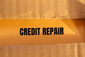 Credit repair message written on ripped torn cardboard paper with orange background. Conceptual credit repair symbol. Copy space. photo
