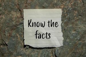 Know the facts message written on ripped torn paper piece with stone background. Conceptual know the facts symbol. Copy space. photo