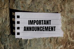 Important announcement message written on ripped torn paper piece with stone background. Conceptual important announcement symbol. Copy space. photo