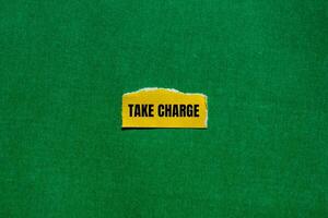 Take charge message written on ripped torn yellow paper piece with green background. Conceptual take charge symbol. Copy space. photo