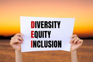Diversity equity and inclusion words written on white paper with blurry lake background. Conceptual diversity equity inclusion DEI symbol. Copy space. photo