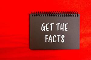 Get the facts message written on black notebook page with red background. Conceptual get the facts symbol. Copy space. photo