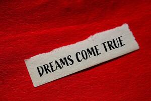 Dreams come true message written on torn paper with red background. Conceptual dreams come true symbol. Copy space. photo
