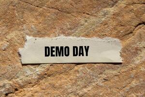 Demo day message written on ripped torn paper piece on stone background. Conceptual demo day symbol. Copy space. photo