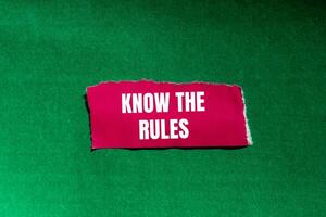 Know the rules words written on ripped torn pink paper piece on green background. Conceptual know the rules symbol. Copy space. photo