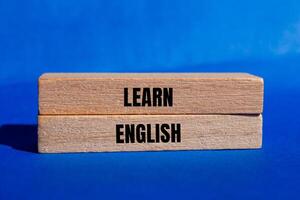Learn english message written on wooden blocks with blue background. Conceptual learn english symbol. Copy space. photo