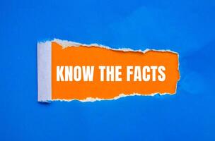 Know the facts message written on ripped torn blue paper with orange background. Conceptual know the facts symbol. Copy space. photo