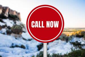 Call now message written on red round sign on nature background. Conceptual call now symbol. Copy space. photo