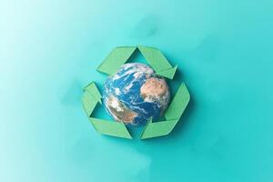 Earth Surrounded by Green Recycling Arrows on a Turquoise Background Symbolizing Environmental Conservation photo