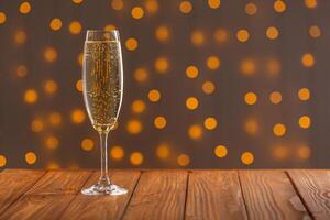 Glasses with champagne on a wooden background against a bokeh background of lights photo