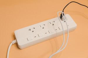 Electrical plug in outlet socket at home, Electrical plug in outlet socket at home, Energy efficiency concept, Power strip with extension cord on beige background, top view. photo