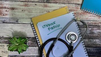 Concept of Uterine Fibroid write on book isolated on Wooden Table. photo