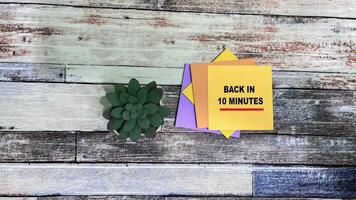 Concept of Back in 10 Minutes write on sticky notes isolated on Wooden Table. photo