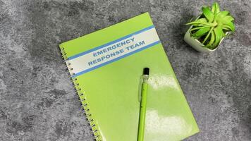 Concept of Emergency Response team write on book isolated on Wooden Table. photo