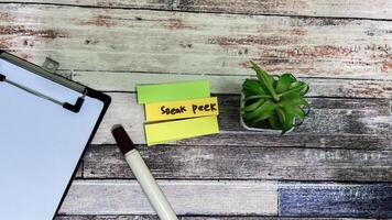Concept of Sneak Peek write on sticky notes isolated on Wooden Table. photo