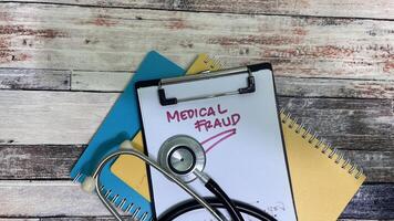 Concept of Medical Fraud write on paperwork isolated on wooden background. photo