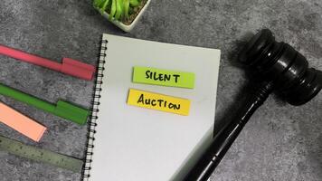 Concept of Silent auction write on sticky notes isolated on Wooden Table. photo