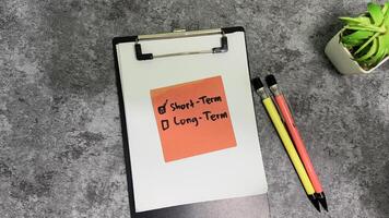 Concept of Short-term write on sticky notes isolated on Wooden Table. photo