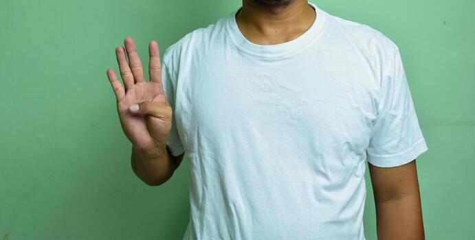 young fair-skinned male keeping hand raised while counting with fingers to talk to deaf person, using sign language photo