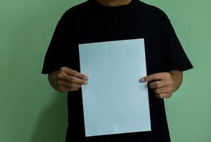 A man holding a blank piece of paper in vertical orintation. Mockup of person with statement or message photo