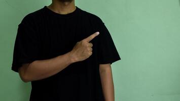 Young man looks and points finger to side at mock-up space for you presentation photo