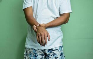 Young man having body pain on green background, medical health concept photo