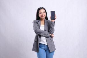 gesture young beautiful office woman asia smile to mobile phone arms crossed holding showing cellphone screen wearing grey suit isolated on white background. for technology, lifestyle, promotion photo
