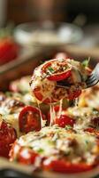 A fork is holding up one slice of stuffed bell pepper with mozzarella and tomatoes with blur background photo