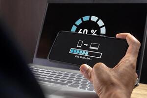 Man transfer files from mobile phone to laptop. Backup, Copy file and media or exchange data concept. photo
