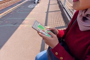 An Asian woman wearing hijab using a map application in photo