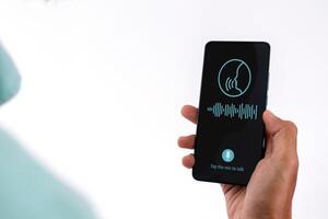 Man gives a voice command or voice assistant to a smart home application on his smartphone photo