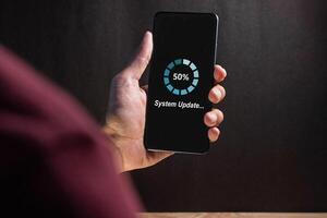 Hand holding a smartphone with software system or application update process on screen photo