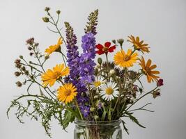 Elegant Bouquet of Wildflowers in a Clear Glass Jar Against a Plain Background photo