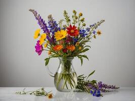 Arrangement of vibrant wildflowers in a clear glass pitcher on a marble surface photo