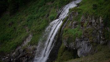 A Serene Waterfall Gracefully Flowing Over Majestic Green Cliffs Into Clear Pools Below video