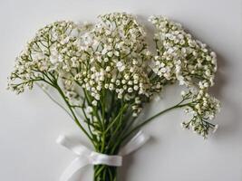 A bouquet of delicate white baby s breath flowers elegantly tied with a white satin ribbon against a pristine backdrop photo
