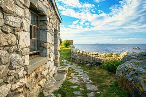 Stone-built house stands gracefully, its facade telling tales of time, with the vast, tranquil sea in the backdrop, creating a serene and timeless landscape. photo