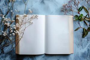 Open book with blank pages on a textured blue surface with botanical elements, evoking inspiration for a creative writing course for young authors. photo