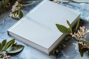 White blank book cover with artistic marbled background and a delicate branch of pink buds, symbolizing the creative potential for young authors. photo