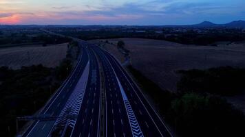 Vehicles navigating a twilight highway surrounded by scenic fields video